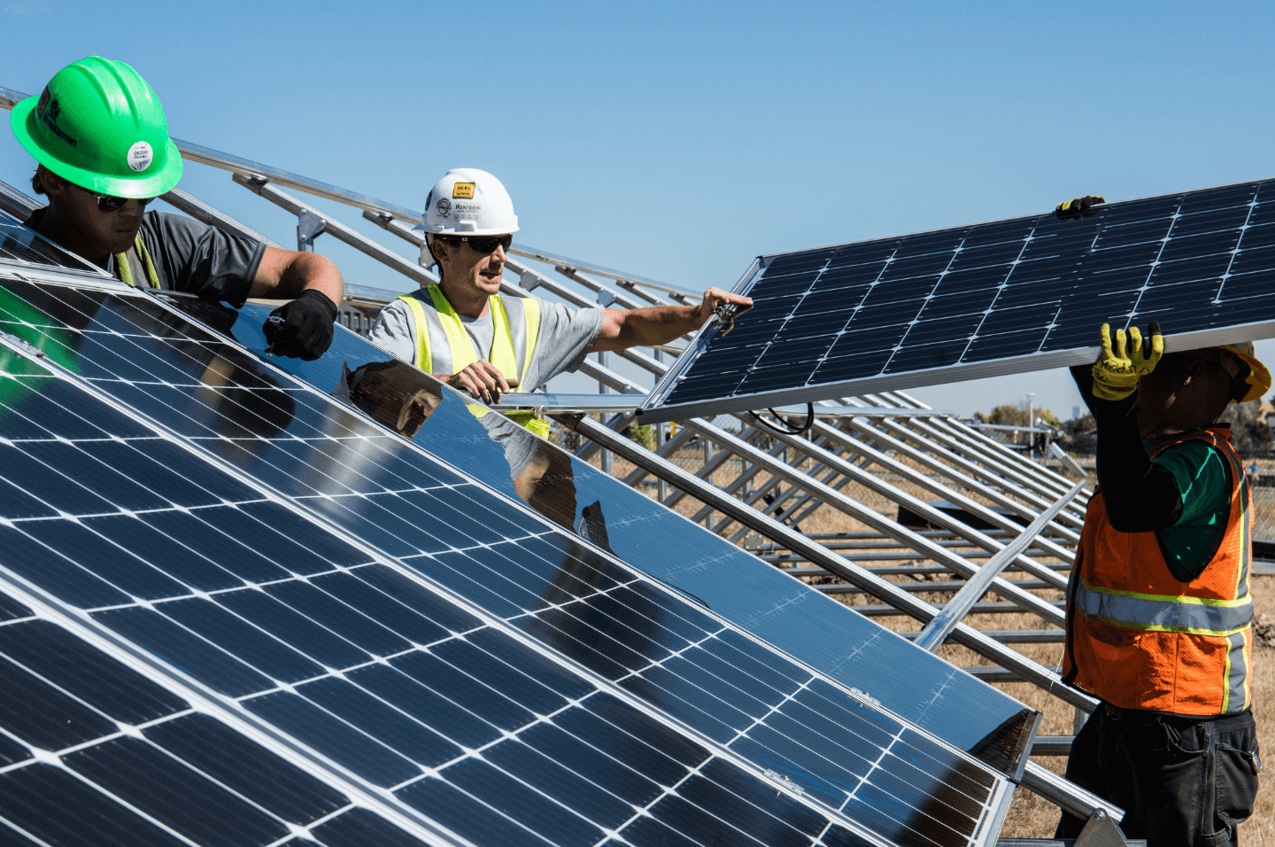 Technicians installing solar panels at a solar farm