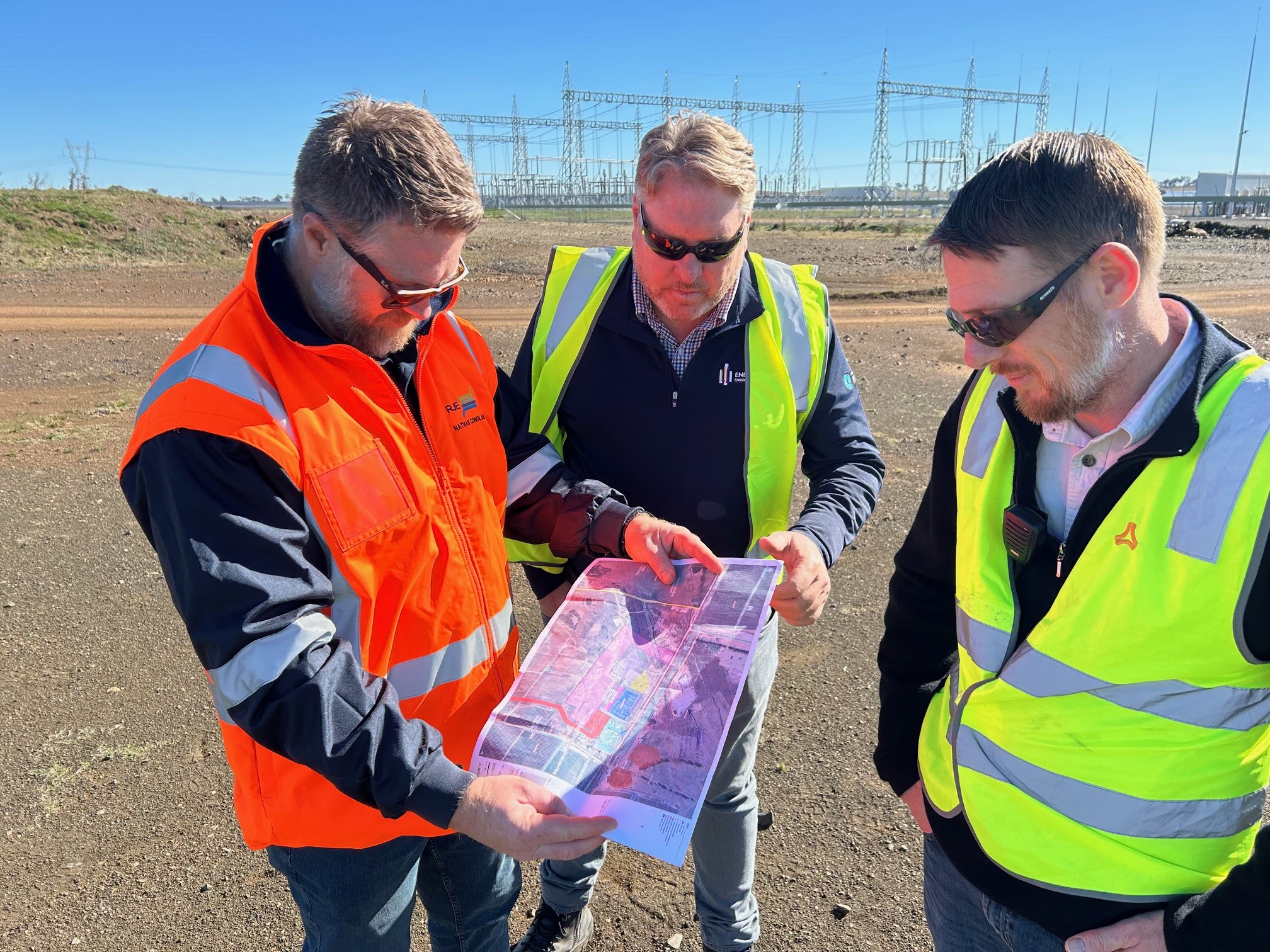 3 people looking at map on solar farm