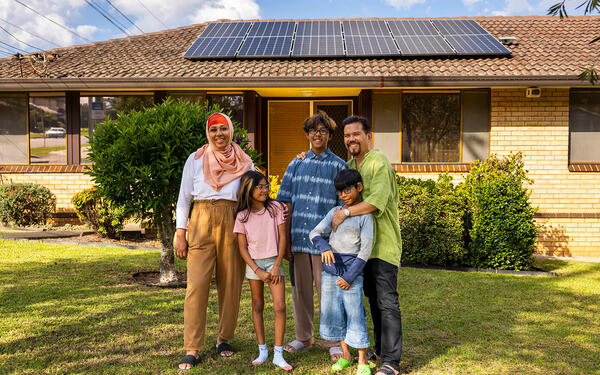 Family standing in front of home with solar panels