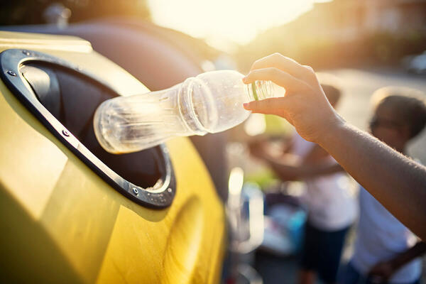 Stock image of person putting plastic bottle in recycling bin