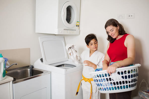 Mother and son loading washing to a washing machine