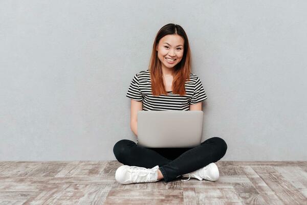 A woman sitting on the floor with a laptop on her lap