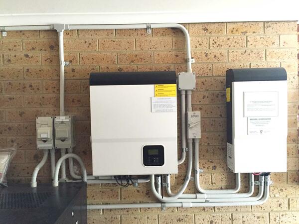 Solar system battery inverter mounted on a brick garage wall