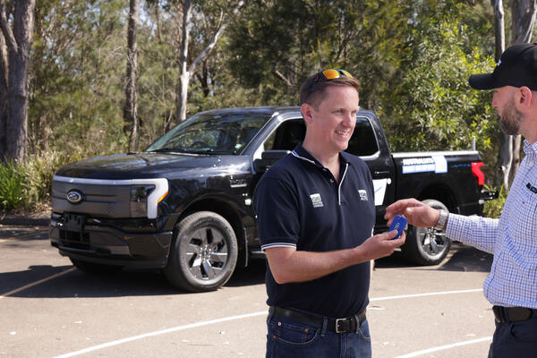 Two people standing in front of an EV truck