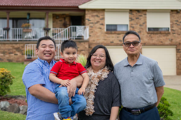 Smiling family standing in front of home